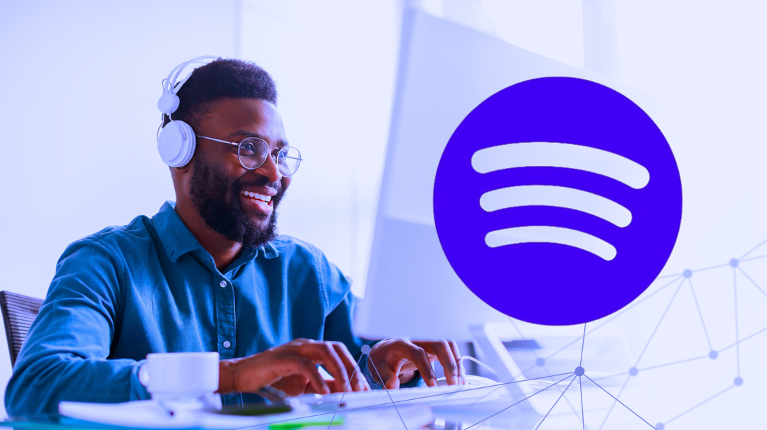 A young African American artist is focused on his work while wearing headphones in a contemporary office setting.